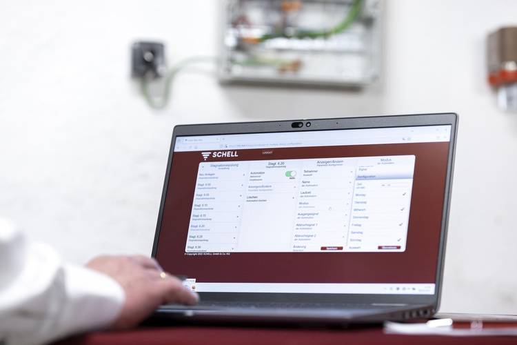 Optimierter ALT-Text: "Fachplaner nutzt Laptop mit geöffneter Gebäudeleittechnik-Software zur Steuerung von Heizungs-, Lüftungs- und Sanitärsystemen; im Hintergrund unscharfe Schalteinheit eines modernen Technikraums.