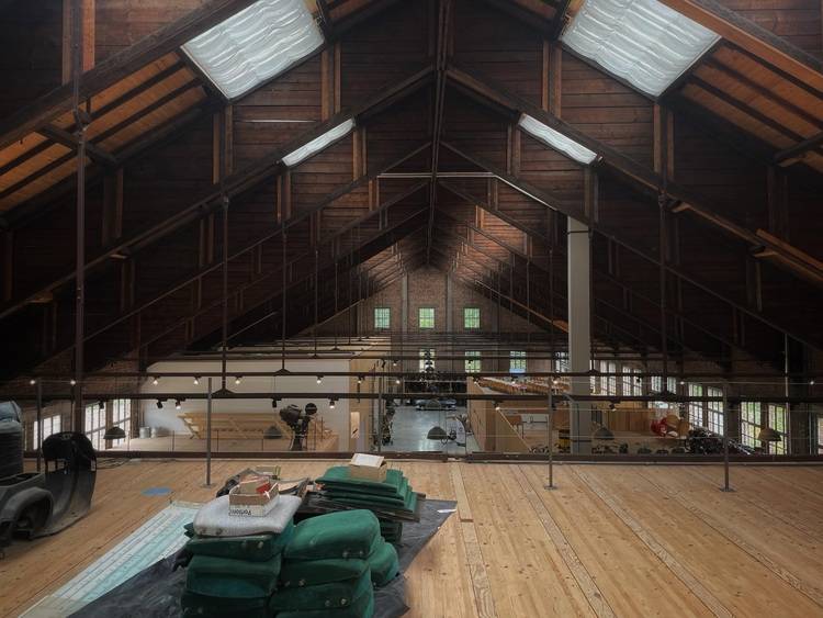 Optimierter ALT-Text: "Geräumiges, modern saniertes Dachgeschoss mit sichtbaren Holzbalken, energieeffizienten Dachfenstern und hochwertigen Dämmmaterialien; im Vordergrund grüne Schallschutz-Isoliermatten für den Einsatz in Gebäudetechnik-Sanierungsprojekten.