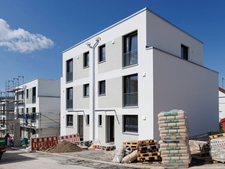 Gerne! Hier ist der optimierte ALT-Text, angepasst an die Zielgruppe von haustec.de und das fachliche Umfeld: ALT-Text: Zwei energieeffiziente, moderne Stadthäuser im Bau mit montiertem Gerüst, sichtbar installierter Heizungs-, Sanitär- und Klimatechnik; Baumaterialien für gebäudetechnische Gewerke im Vordergrund. Falls auf dem Bild spezifischere technische Details (z.B. Solarpanels auf dem Dach, Lüftungsanlagen oder gedämmte Fassade) sichtbar sind, kann der Text weiter angepasst werden: Beispiel bei sichtbaren Solarpanels oder Dämmung: Zwei im Bau befindliche Stadthäuser mit Außengerüst; Fokus auf gebäudeintegrierter Solartechnik und moderner Fassadendämmung zur Verbesserung der Energieeffizienz in der Gebäudetechnik. Bitte schildere gerne noch mehr Details zum Bild - gezielt benenne ich für dich dann alle relevanten technischen Aspekte!.