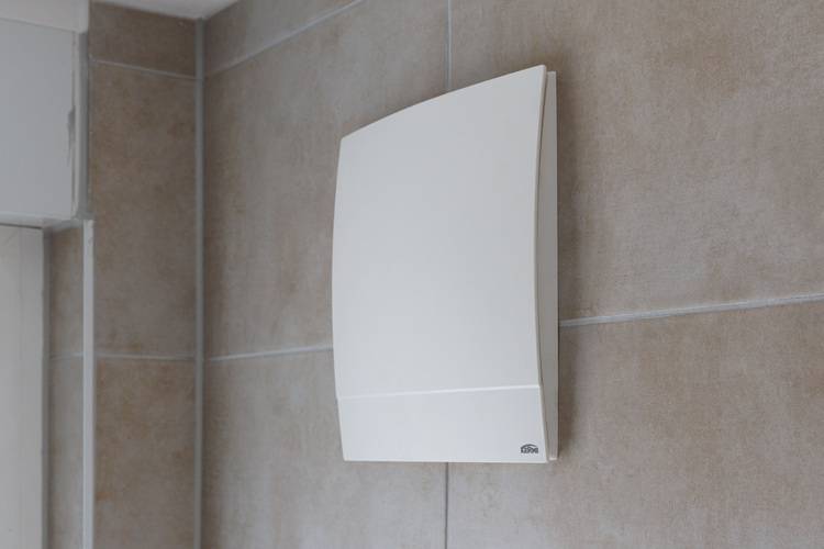 Gerne! Hier ist ein optimierter, fachlich präziser ALT-Text für das beschriebene Bild - zugeschnitten auf die Zielgruppe und den Kontext: ALT-Text: Kompakter, energieeffizienter Abluftventilator für Badezimmer mit automatischem Feuchtesensor, installiert an einer beigefliesten Wand - typisches Beispiel moderner Lüftungslösungen in der Gebäudetechnik zur Verbesserung des Raumklimas und zur Einhaltung aktueller EnEV-Vorgaben. Falls Details wie Hersteller, Modell oder besondere technische Merkmale erkennbar sind (z. B. Schallschutzgehäuse, Rückschlagklappe o. Ä.), können diese gern noch ergänzt werden, um den Barrierefreiheitsanspruch weiter zu erfüllen.