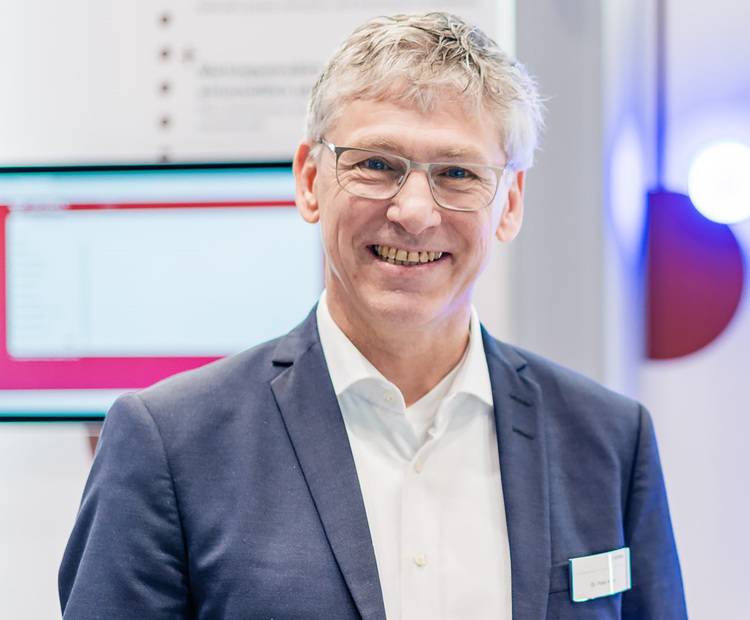 Gerne! Hier ist ein themenrelevanter, optimierter ALT-Text für das beschriebene Bild passend zur Zielgruppe von haustec.de: Optimierter ALT-Text: "Geschäftsmann im dunkelblauen Anzug mit Brille steht in einem modernen Bürogebäude; im unscharfen Hintergrund ist ein großflächiger Bildschirm mit technischen Gebäudedaten zu erkennen - Symbolbild für Entscheider in der Gebäudetechnik." Falls Sie besondere Themen betonen möchten (z.B. Digitalisierung, Energieeffizienz, TGA-Planung), kann der Text weiter angepasst werden: Alternative mit Schwerpunkt Digitalisierung: "Entscheider der Gebäudetechnikbranche im dunkelblauen Anzug steht vor digitaler Präsentation technischer Gebäudeautomation - Fokus auf Digitalisierung und smarte Lösungen." Bitte geben Sie mir gerne mehr Kontext oder Wunsch-Schwerpunkte für eine noch gezieltere Anpassung!.