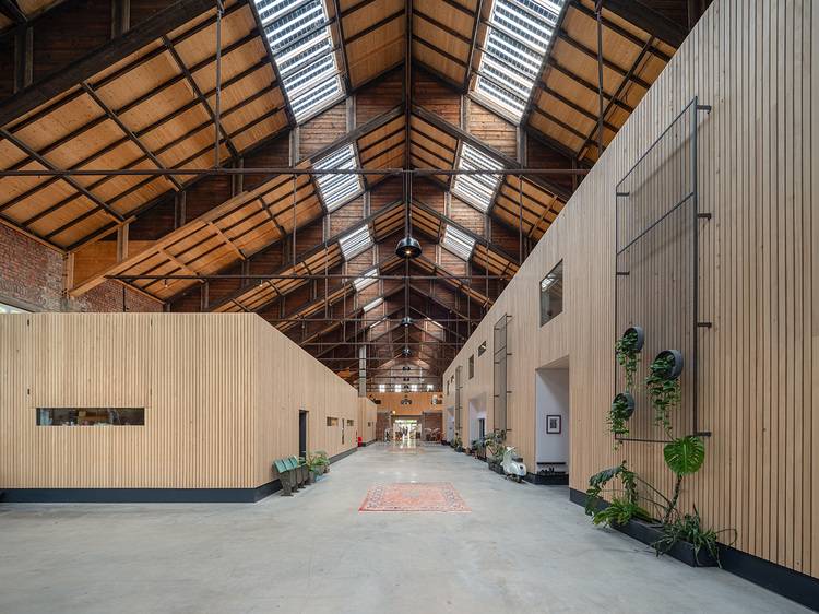 Innenraum eines modernen Gebäudes mit sichtbaren Holz-Wandverkleidungen, offenem Dachstuhl und großen Oberlichtern; die Ausstattung zeigt beispielhaft energieeffiziente Bauweise und natürliche Belüftung - relevant für TGA-Planer, Architekten und Entscheider in der Gebäudetechnik.