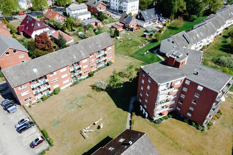 Luftaufnahme mehrerer Mehrfamilienhäuser mit begrünten Außenanlagen und Parkplätzen, Fokus auf Energieeffizienz und moderne Gebäudetechnik im Wohnquartier.