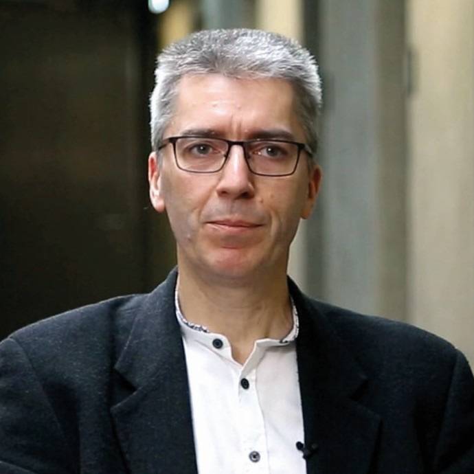 Branchenexperte der Gebäudetechnik mit grauen Haaren, Brille und dunklem Sakko blickt im Interview bei haustec.de in die Kamera.