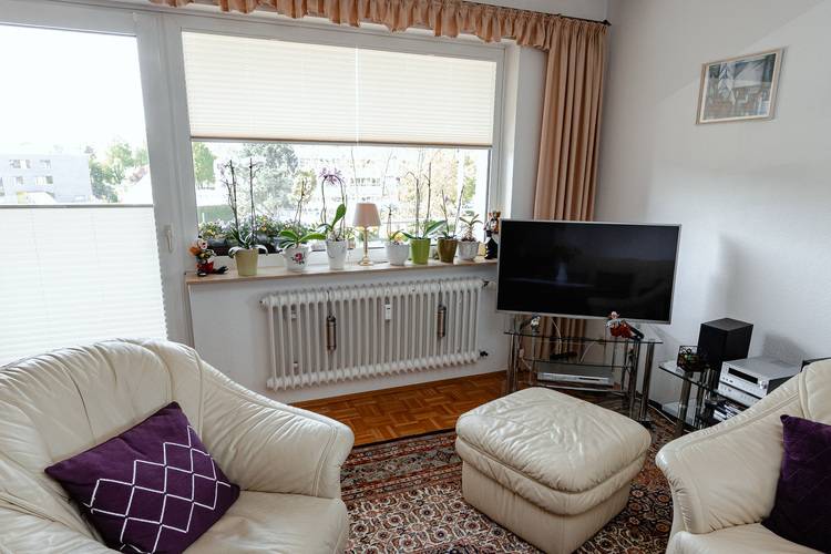 Heller Wohnraum mit energieeffizientem Fenster, moderner Heizlösung, weißen Stühlen und smart integrierter Gebäudetechnik im Lebensraum.