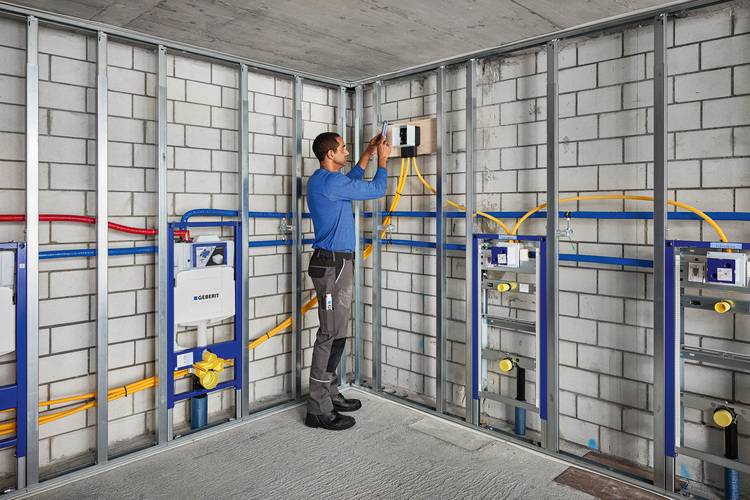 Fachhandwerker installiert neue Sanitär- und Elektroinstallationen im Rohbau, sichtbare Leitungsführung und offene Wandkonstruktion in Gebäudetechnik.