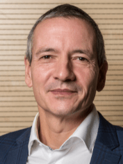 Porträt eines mittleren Alters Manns im blauen Anzug vor beigem Hintergrund, geeignet für Expertenbeiträge zur Gebäudetechnikbranche.