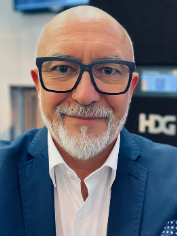 Portrait eines lächelnden, glatzköpfigen Experten mit Brille und weißem Bart im blauen Anzug - Referent auf einer Fachmesse für Gebäudetechnik.