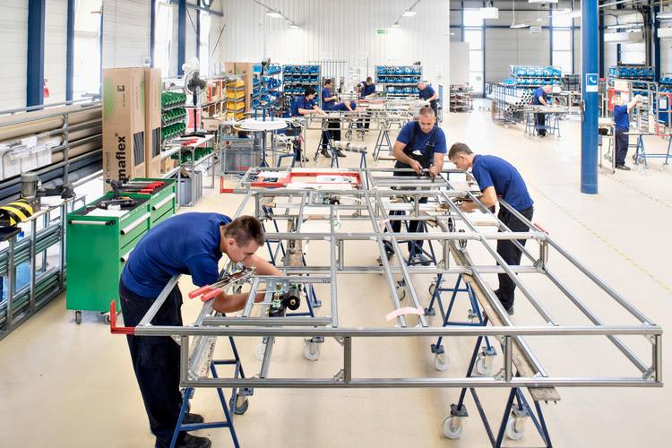 Fachkräfte fertigen Metallrahmen für Gebäudetechnik in heller, strukturierter Werkstatt - Fokus auf industrieller Fertigung und Qualitätssicherung.