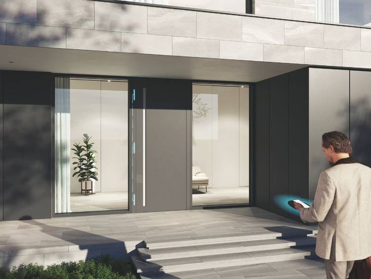 Fachkraft steht mit Tablet vor modernem Gebäudeeingang mit Glasfront, geeignet für smarte Gebäudetechnik- oder Energieeffizienz-Themen.