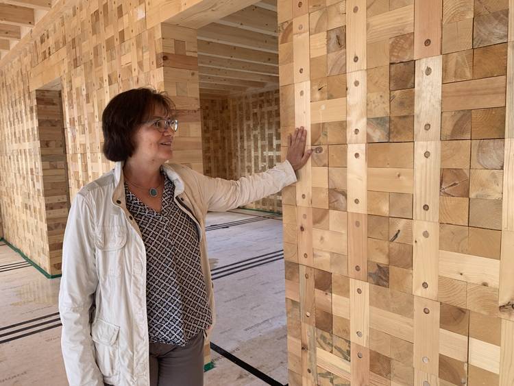Fachfrau prüft eine innovative Innenwand aus ineinandergreifenden Holzbausteinen; Beispiel für nachhaltige Gebäudetechnik und moderne Gebäudehülle.