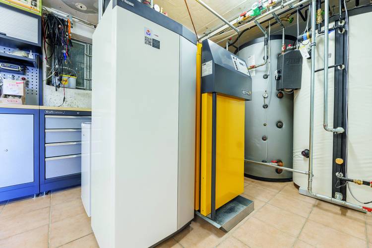 Zwei moderne Heizungsanlagen mit großen Warmwasserspeichern in hellem Technikraum mit Fliesenboden, typisch für zeitgemäße Gebäudetechnik.