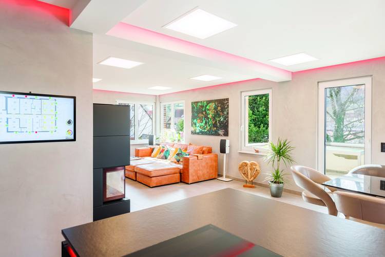 Modernes Wohnzimmer mit integrierter Smart-Home-Steuerung, energieeffizienten Fenstern, moderner Anlagentechnik und großflächigen Verglasungen.