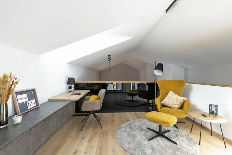 Moderner Arbeitsbereich im Dachgeschoss mit gelbem Stuhl, Schreibtisch und Lampe - Beispiel für effiziente Raumnutzung in der Gebäudetechnik.