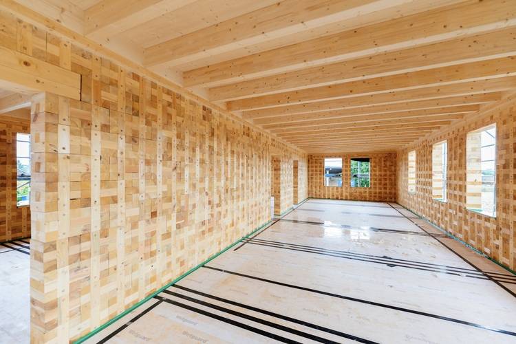 Rohbau eines Gebäudes: Sichtbare Holztragkonstruktion, unbehandelte Holzdecken und Wände, Fokus auf moderne Bauweise in der TGA-Branche.