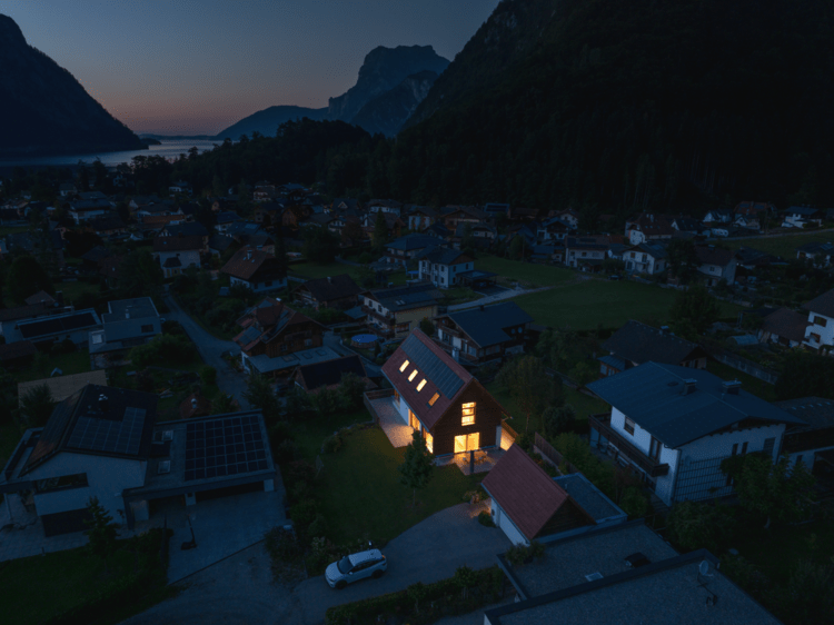 Gebäude im Gebirgsdorf mit moderner Außen- und Innenbeleuchtung, Fokus auf energieeffiziente Lichttechnik für die Gebäudetechnikbranche.