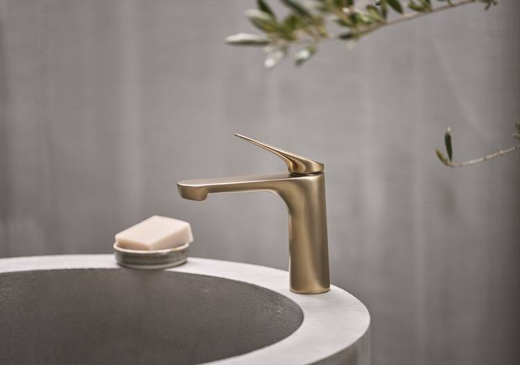 Moderne, goldene Armatur mit Seifenablage auf rundem Beton-Waschbecken; Designlösung für gehobene Sanitäranlagen im Gebäudebereich.