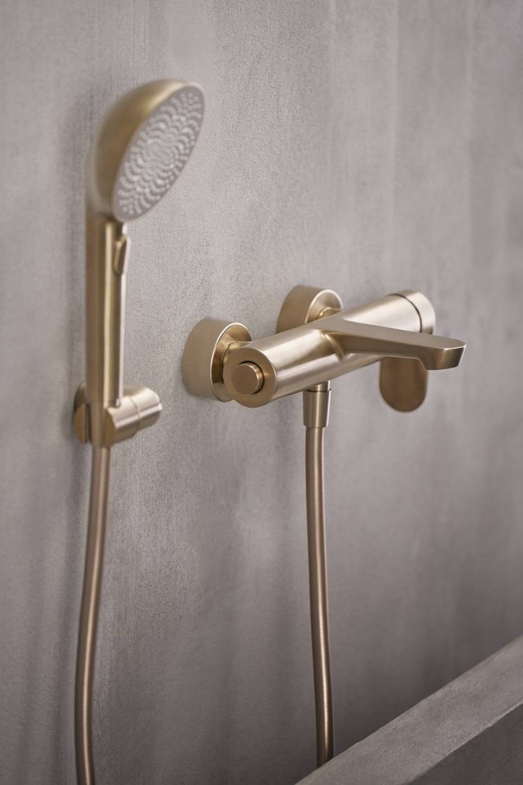 Modernes Duscharmatur-Set in Goldoptik, wandmontiert auf grauer Badezimmerfliese - Beispiel für designorientierte Sanitärinstallation in der Gebäudetechnik.