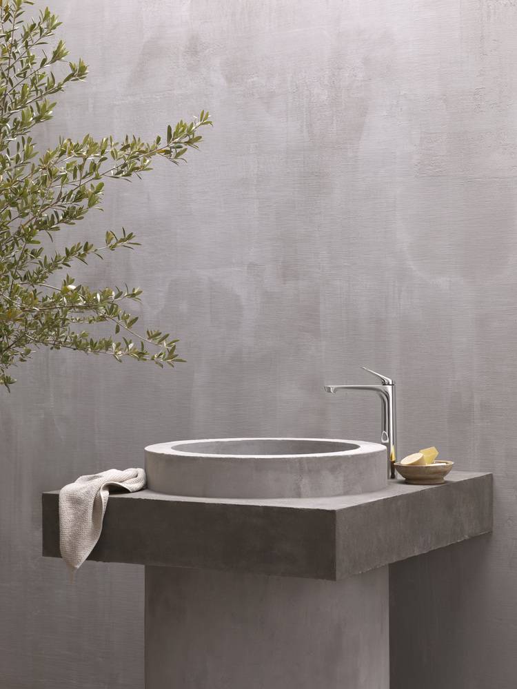 Moderner Waschtisch aus Beton mit Handtuch und Seifenspender, installiert vor grauer Wand - Beispiel für zeitgemäße Sanitärtechnik im Objektbau.