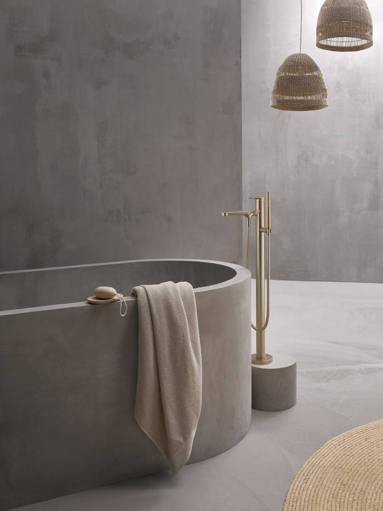 Freistehende, moderne Badewanne in Grau mit Handtuch, Aufsatzarmatur und Pendelleuchten - Beispiel für zeitgemäße Badausstattung in der Gebäudetechnik.