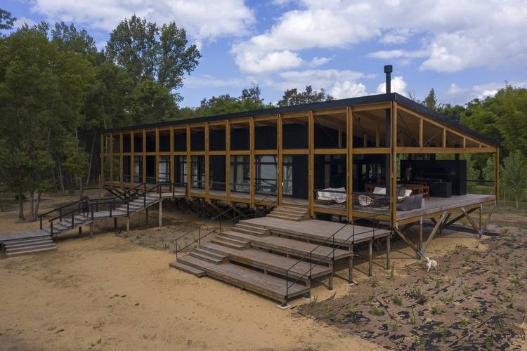 Modernes Holzhaus auf Stelzenbauweise mit großem Terrassendeck, Beispiel für energieeffiziente Gebäudehülle im Kontext nachhaltiger Gebäudetechnik.