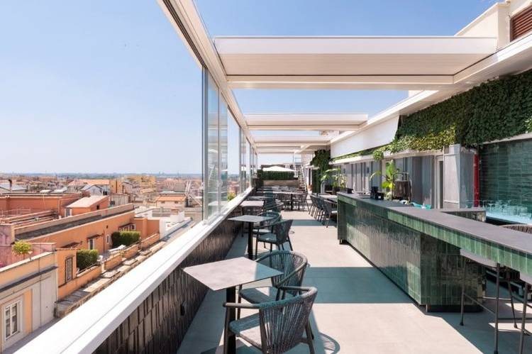 Dachterrasse mit begrünten Fliesen, Sitzbereichen und Blick auf die Stadt als Beispiel für energieeffiziente Gebäudetechnik im urbanen Raum.
