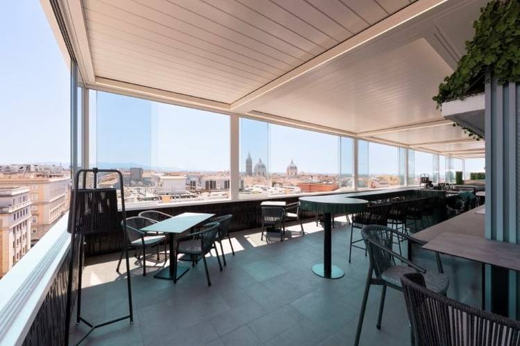 Moderne Dachterrasse mit Sitzgruppen, großen Glasflächen und Blick auf die Stadt, Beispiel für nachhaltige Gebäudeplanung und energieeffiziente Architektur.