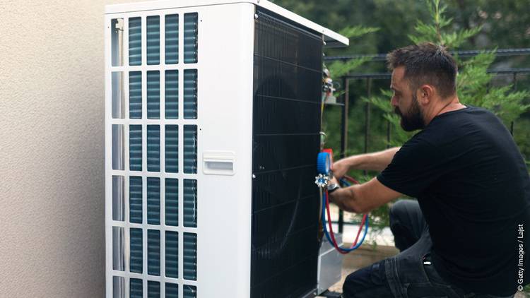 Ein SHK-Fachhandwerker wartet eine Klimaanlage in einem Technikraum - Fokus auf Gebäudetechnik, Wartung und energieeffiziente Klima-Systeme.