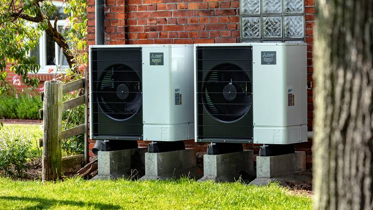 Zwei Wärmepumpen-Außengeräte auf Betonsockeln an Klinkerhaus, installiert nach aktuellen TGA-Standards; geeignet für energieeffiziente Gebäudetechnik.