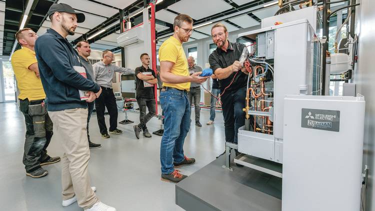 Fachleute aus der Gebäudetechnik begutachten und analysieren die Komponenten einer großen Klimaanlage in einer modernen Werkstattumgebung.