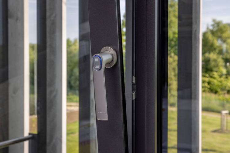 Detailansicht eines modernen, barrierearmen Türgriffs an einer Glastür, geeignet für öffentliche Gebäude, mit Blick ins energieeffiziente Außengebiet.