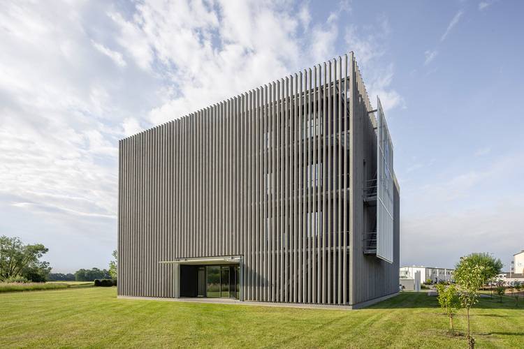 Modulares, würfelförmiges Gebäude mit vertikalen Fassadenlamellen; Beispiel moderner Gebäudehülle für energieeffiziente Gebäudetechnik.