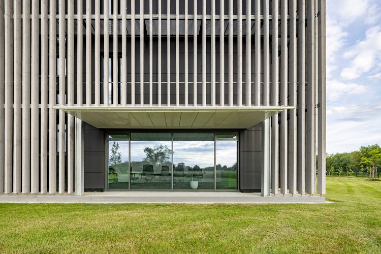 Fassade eines modernen Gebäudes mit vertikalen Lamellen und Glasfassade, Beispiel für energieeffiziente Gebäudehülle in der Gebäudetechnik.