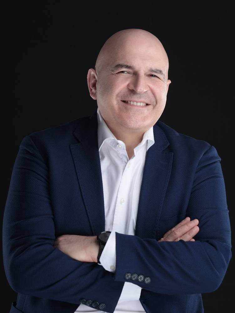 Geschäftsmann im Anzug, Experte für Gebäudetechnik, steht mit verschränkten Armen vor dunklem Hintergrund, geeignet für haustec.de-Fachartikel.