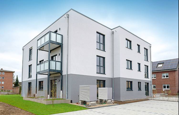 Modernes Mehrfamilienhaus mit drei Etagen, großen Fenstern und Balkonen - Beispiel für energieeffiziente Gebäudehülle in der TGA.