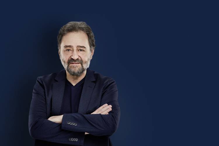 Porträt eines Geschäftsmannes im dunklen Anzug vor blauem Hintergrund, typisch für Entscheider in der Gebäudetechnikbranche.