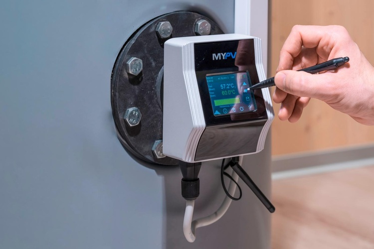 Fachkraft bedient mit einem Stylus ein digitales Bedienpanel an einer HLK-Anlage zur Steuerung und Überwachung von Gebäudetechniksystemen.