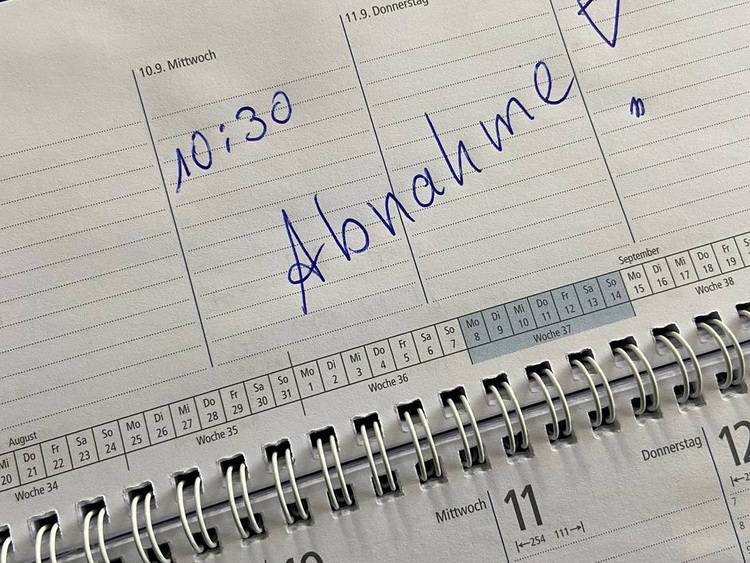 Nahaufnahme eines Terminplaners: Am 10. September ist um 10:30 Uhr die Baustellenabnahme handschriftlich in blauer Tinte notiert.