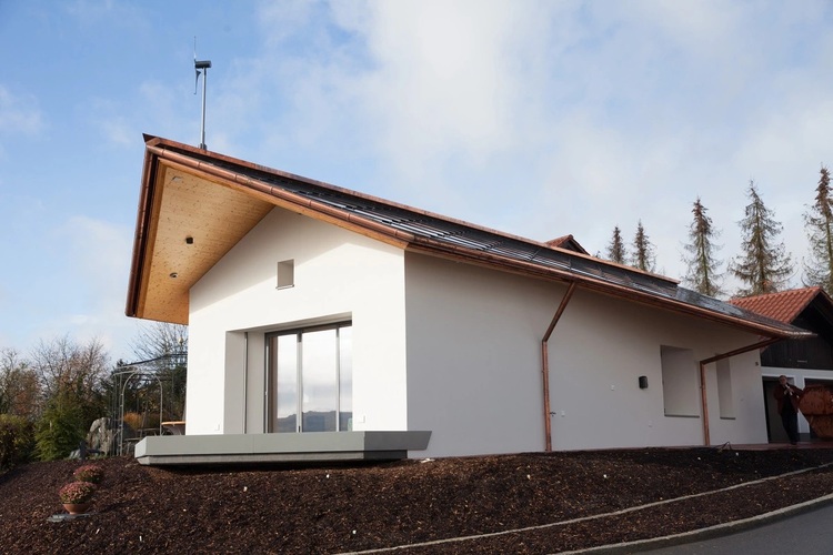 Modernes Einfamilienhaus mit geneigtem Dach, PV-Anlage und großen Fenstern, Fokus auf Gebäudehülle und Energieeffizienz für TGA-Fachpublikum.