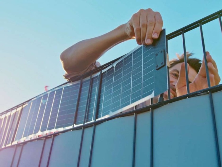 Fachkraft montiert PV-Modul an Metallzaun bei Sonnenschein - Anwendung innovativer Solartechnik im Bereich Gebäudetechnik und erneuerbare Energien.