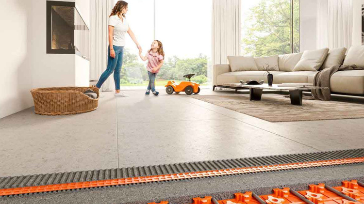 Modernes Wohnzimmer mit sichtbarer Fußbodenheizung, Mutter und Tochter stehen auf dem System. Sichtbar ist ein Spielzeugauto am Rand.