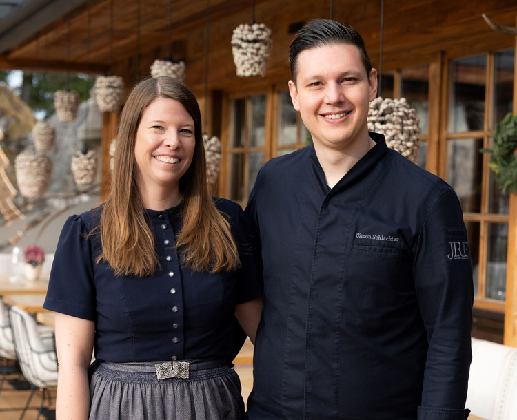 Zwei Fachkräfte aus der Gebäudetechnikbranche stehen auf einer Holzterrasse bei einem Branchenevent im Austausch, dekoriert mit technischen Elementen.