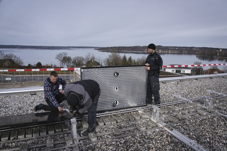 Fachkräfte montieren Photovoltaikmodul auf Flachdach inkl.. Montageschienen und Werkzeugen, ideal für energieeffiziente Gebäudehülle.