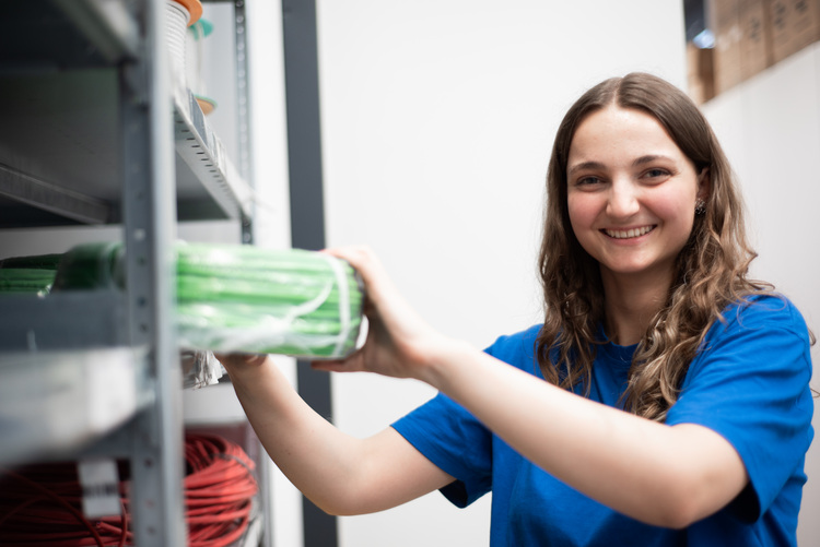 Fachkraft prüft und sortiert grüne Installationskabel im Techniklager - Lagerorganisation in der Gebäudetechnikbranche.