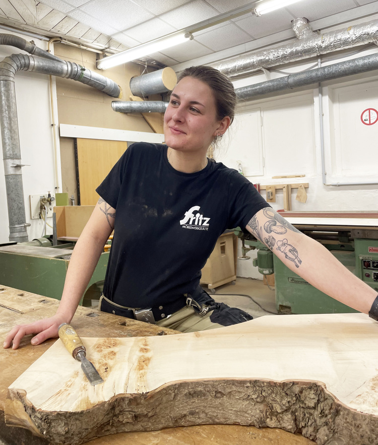 Fachkraft in Werkstatt arbeitet an großem Holzelement mit Werkzeugen - Illustration für handwerkliche Fertigung im Bereich Gebäudetechnik.