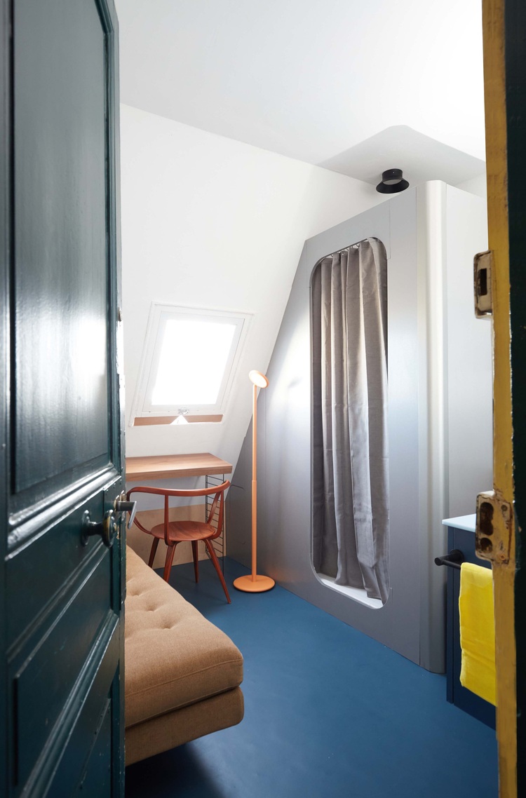 Kleiner, modern eingerichteter Raum mit braunem Sofa, Arbeitsplatz und Tageslicht von Dachfenster, Beispiel für effiziente Flächennutzung in Gebäuden.