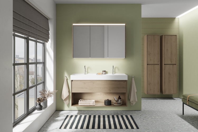Barrierefreies Bad mit grünen Wänden, Doppelwaschtisch und Holzunterschränken, geeignet für zeitgemäße Sanitärtechnik im Objektbau.