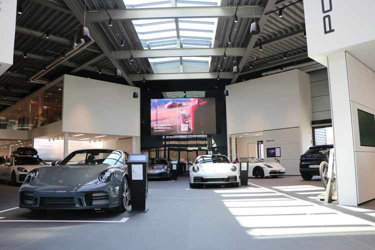 Tageslichtdurchfluteter Showroom mit Glasdach als Beispiel für energieeffiziente Gebäudehülle, darunter mehrere Fahrzeuge ausgestellt.