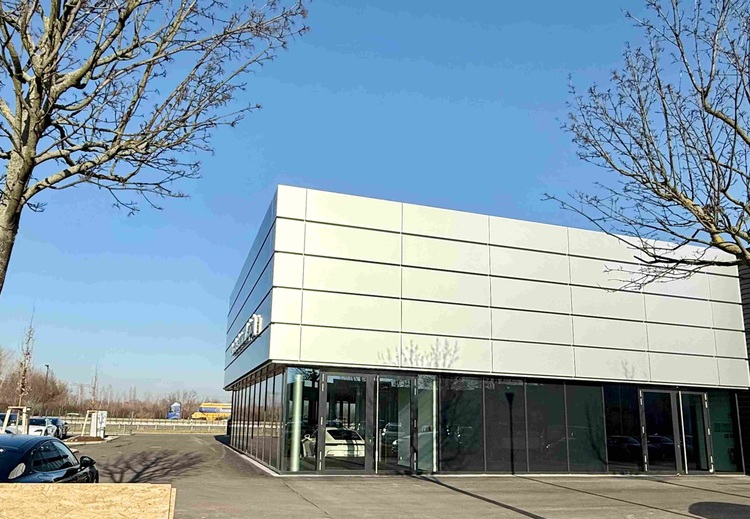 Moderne Gebäudehülle mit Glas- und weißen Fassadenelementen, beispielhaft für energieeffiziente Gebäudetechnik im Tageslicht, vor blauem Himmel.
