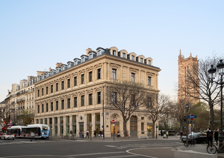 Historisches Gebäude an einer Straßenecke mit Stadtbäumen, Passanten und Fahrzeugen - Beispiel für städtische Gebäudetechnik und Energieeffizienz.